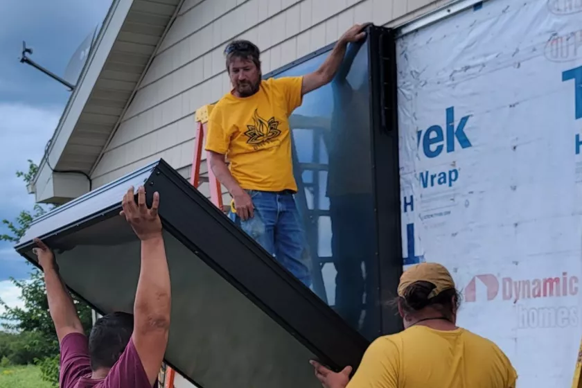 solar thermal panel and people installing it on the side of a house