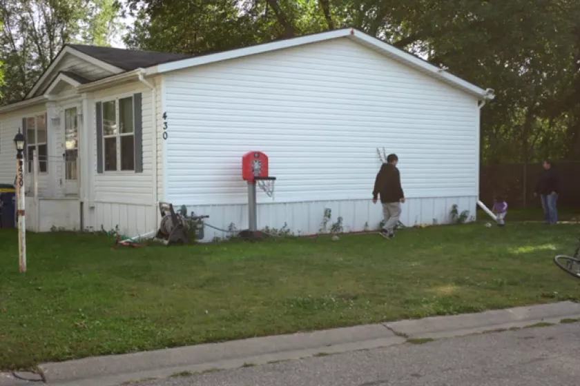 A white manufactured home surrounded by green grass